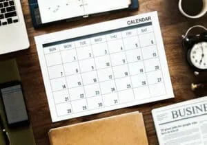 Calendario de mesa con notas y dispositivos de trabajo, ideal para organizar recuerdos y fechas importantes.